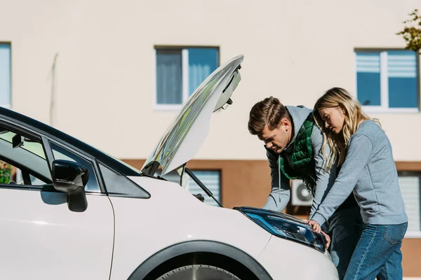 Junges Paar repariert kaputtes Auto auf der Straße — Stockfoto