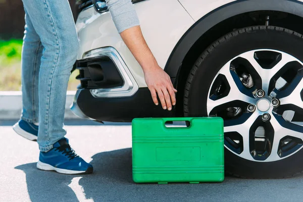 Cropped shot of man holding toolbox while repairing broken car — Stock Photo