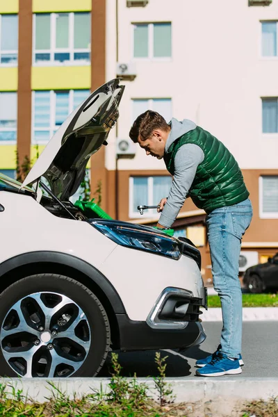 Side view of young man fixing broken car on street — Stock Photo