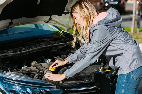 Junge Frau repariert kaputtes Auto auf Straße — Stockfoto