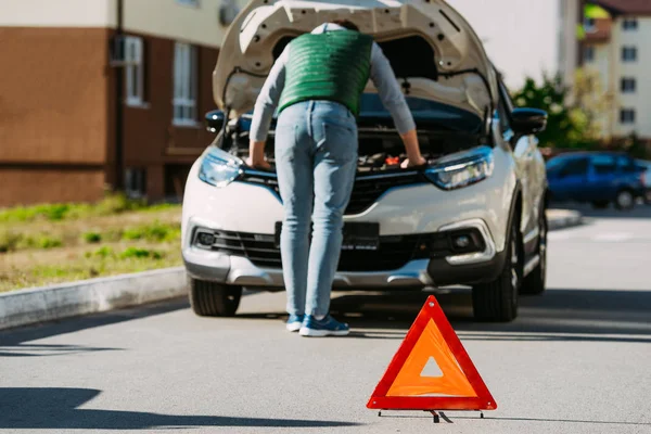 Дорожный знак и вид сзади человека, фиксирующего сломанный автомобиль на дороге — стоковое фото