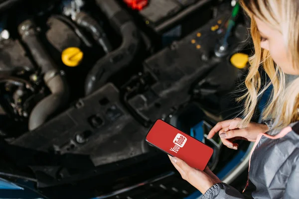 Tiro recortado de mulher usando smartphone com aplicativo youtube durante a reparação de carro quebrado — Fotografia de Stock