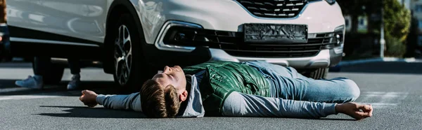 Раненый молодой человек лежит на дороге после автомобильной аварии — стоковое фото