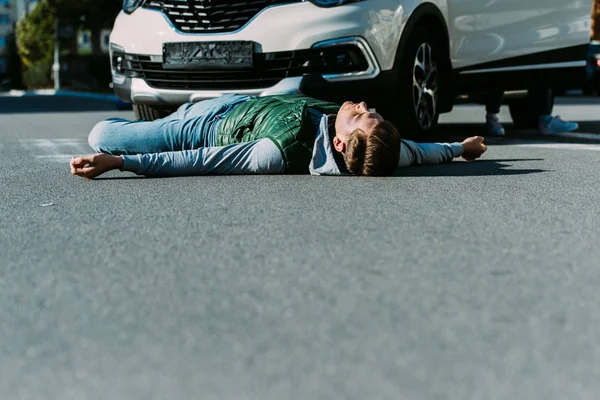 Nivel de superficie del joven lesionado acostado en la carretera después de un accidente de coche - foto de stock