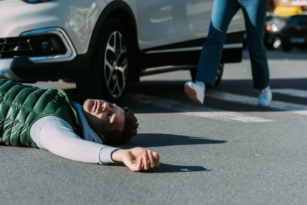 Cropped shot of woman running to victim of car accident lying on road — Stock Photo