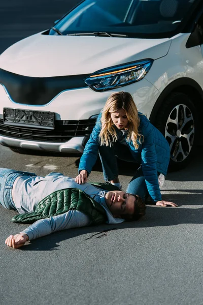 Vue à grand angle de la jeune femme touchant la victime d'une collision automobile — Photo de stock