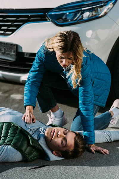 Young woman checking heartbeat of victim after traffic collision — Stock Photo