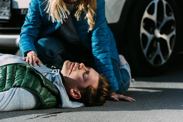 Cropped shot of woman checking heartbeat of victim after traffic collision — Stock Photo