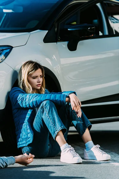 Peur jeune femme assise près de la voiture après un accident de la circulation — Photo de stock