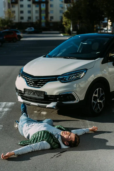 Visão de alto ângulo do homem ferido e do carro na estrada após o acidente de trânsito — Fotografia de Stock