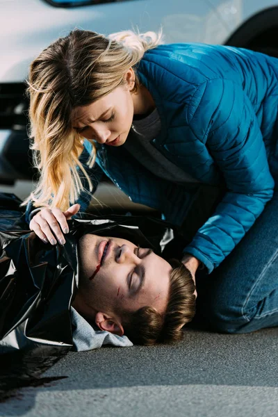 Young woman crying above dead man on road after traffic collision — Stock Photo