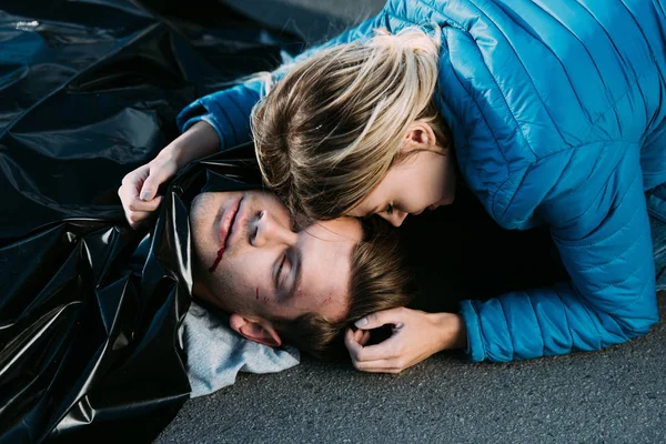 Young woman crying and hugging dead man on road — Stock Photo