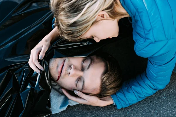 Close-up view of young woman crying and hugging dead man on road — Stock Photo