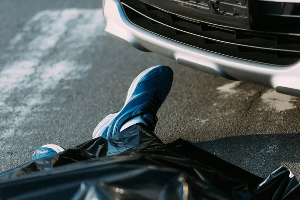 Обрезанный снимок мертвого человека и автомобиля на дороге после ДТП — стоковое фото