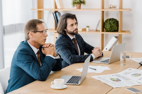 Two attentive adult men sitting at table in insurance office — Stock Photo