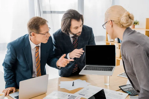 Jovem agente de seguros do sexo masculino em pé com os trabalhadores e apontando para laptop no escritório — Fotografia de Stock