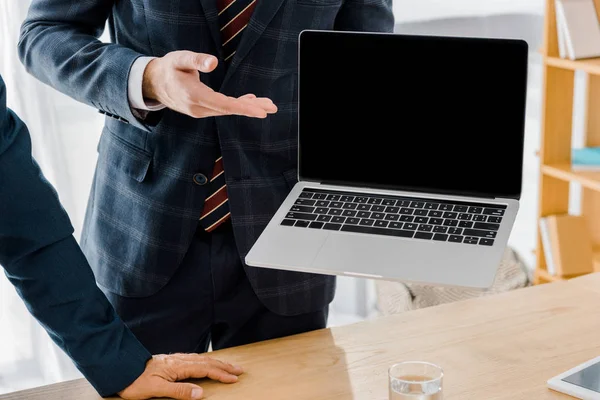 Male insurance agent holding laptop with blank screen in office — Stock Photo