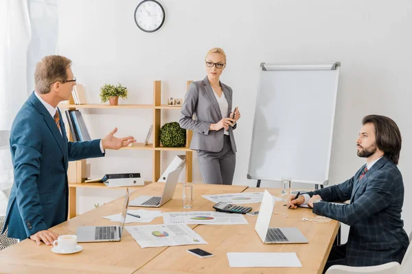 Adult man talking to workers at meeting in office — Stock Photo