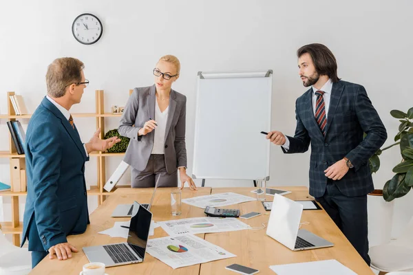 Business people standing near table and having discussion in office — Stock Photo