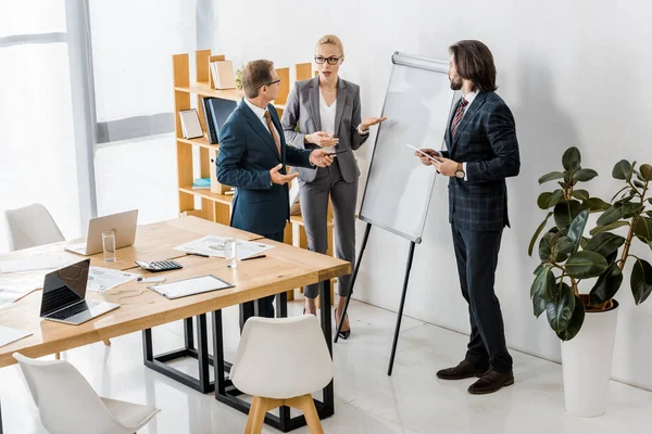 Office workers standing near white board and having discussion — Stock Photo