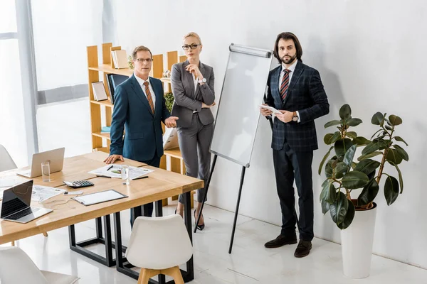 Office workers standing near white board and having discussion — Stock Photo