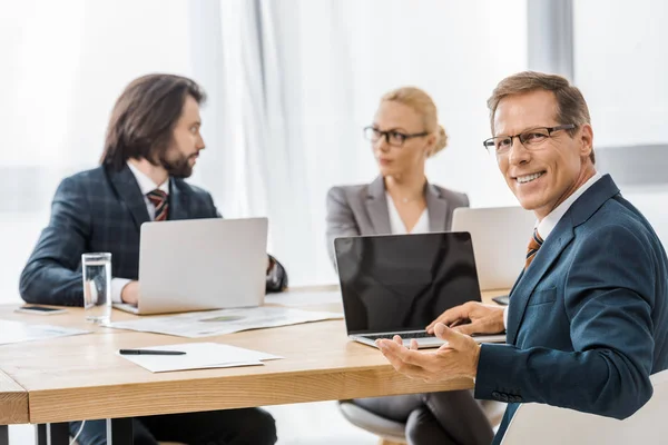 Büroangestellte sitzen bei Besprechung mit Laptops am Tisch — Stockfoto