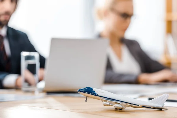 Avion jouet à la table en bois avec employé de bureau sur fond flou — Photo de stock