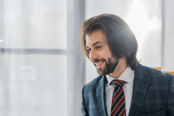 Jovem sorridente empresário em terno de pé no escritório — Fotografia de Stock