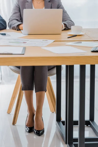 Femme assise avec ordinateur portable à la table dans le bureau — Photo de stock