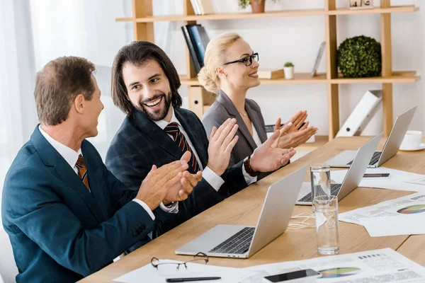 Glückliche Geschäftsleute klatschen bei Treffen im Amt in die Hände — Stockfoto