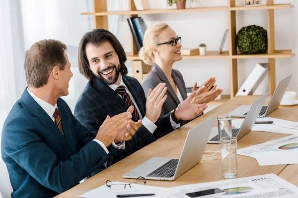 Gente de negocios feliz aplaudiendo las manos en la reunión en la oficina - foto de stock