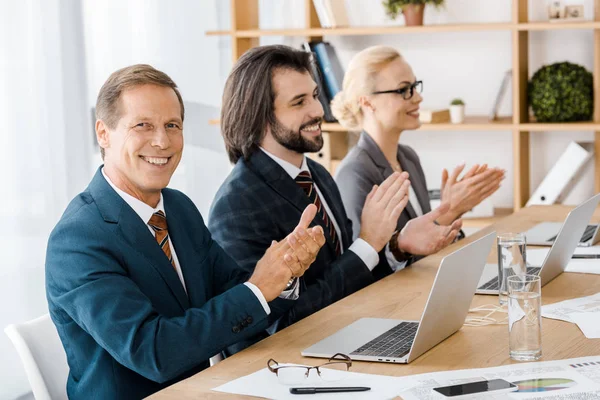 Glückliche Geschäftsleute klatschen bei Treffen im Amt in die Hände — Stockfoto