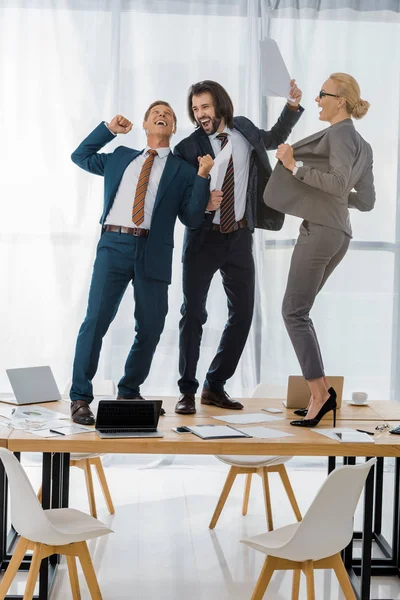 Веселые страховые работники, танцующие на столе на встрече в офисе — стоковое фото