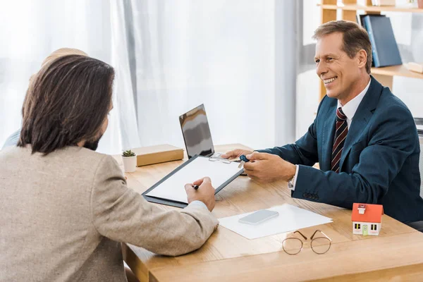 Erwachsener lächelnder Versicherungsvertreter zeigt Mann im Amt Vertrag — Stockfoto
