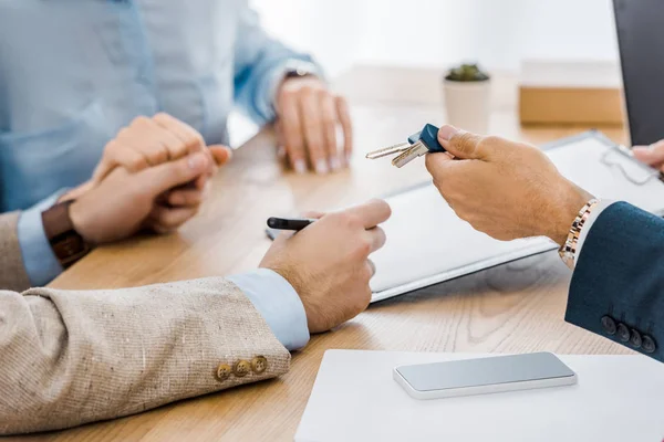 Man holding keys while couple holding hands together — Stock Photo