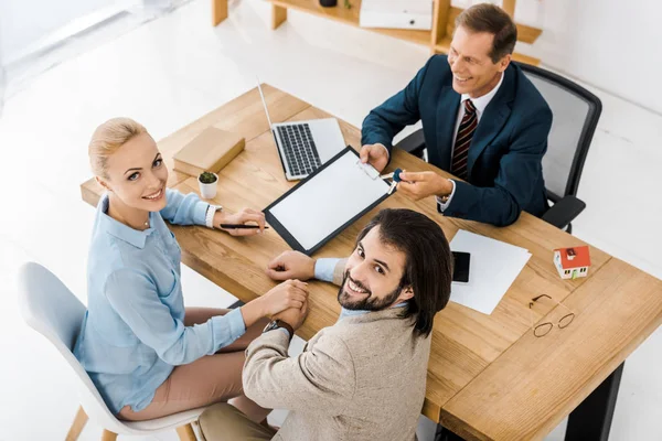 Uomo d'affari dando chiavi e contratto per coppia in ufficio — Foto stock