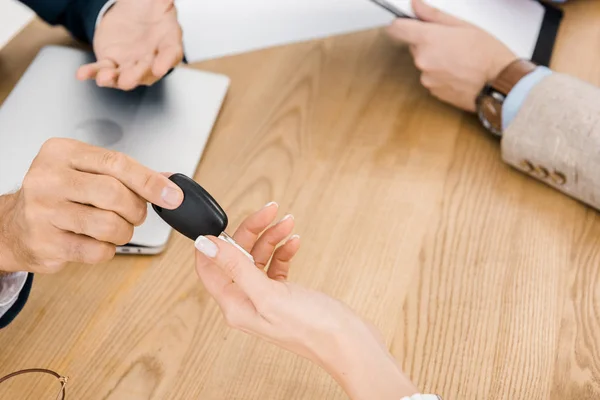 Primer plano del hombre dando la llave a la mujer en la mesa de madera - foto de stock