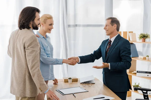 Femme souriante et agent d'assurance serrant la main au bureau — Photo de stock