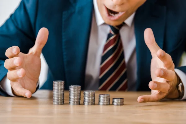 Close up de empresário surpreso olhando para moedas de prata na mesa de madeira — Fotografia de Stock