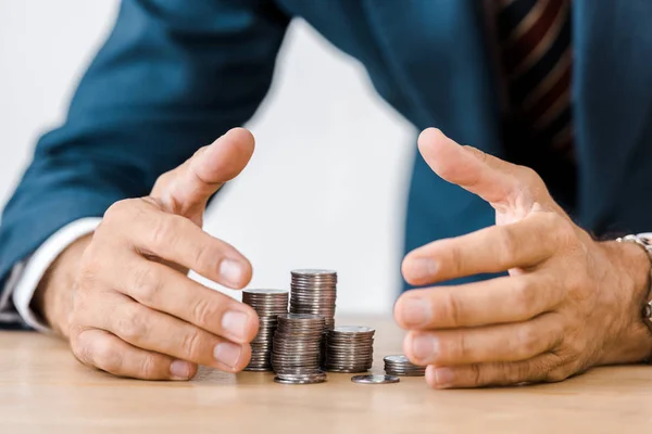 Hombre de negocios agarrando monedas de plata en la mesa de madera - foto de stock