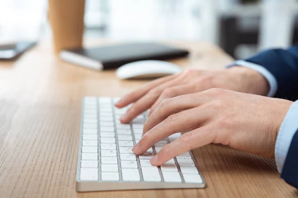 Abgeschnittenes Bild eines Geschäftsmannes, der auf der Computertastatur am Tisch im modernen Büro tippt — Stockfoto