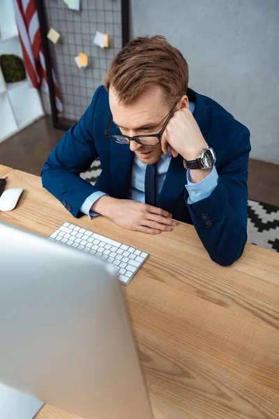 Visão de alto ângulo de homem de negócios em óculos que trabalham à mesa com monitor de computador em escritório moderno — Fotografia de Stock