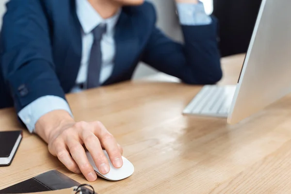 Imagen recortada de hombre de negocios en gafas que trabajan en la mesa con el ratón de la computadora en la oficina moderna — Stock Photo