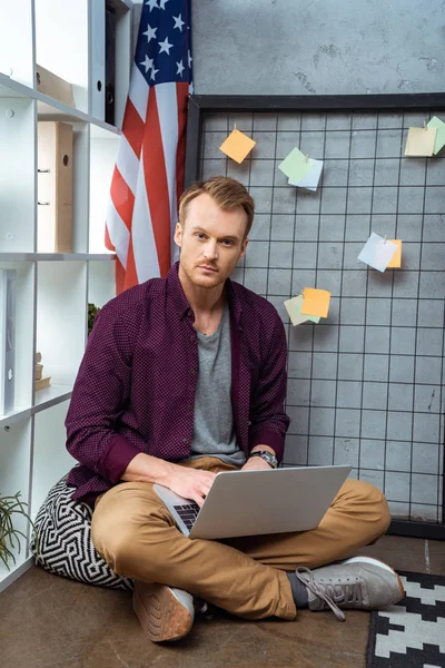 Серьезный молодой мужчина фрилансер, работающий на ноутбуке в домашнем офисе — стоковое фото