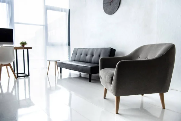 Intérieur du salon moderne avec écran d'ordinateur sur la table, fauteuil et canapé — Photo de stock