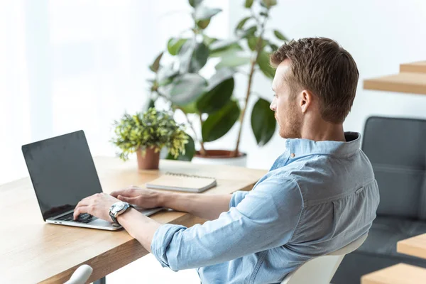 Foyer sélectif des jeunes hommes d'affaires travaillant sur ordinateur portable avec écran blanc à la table dans le bureau — Photo de stock