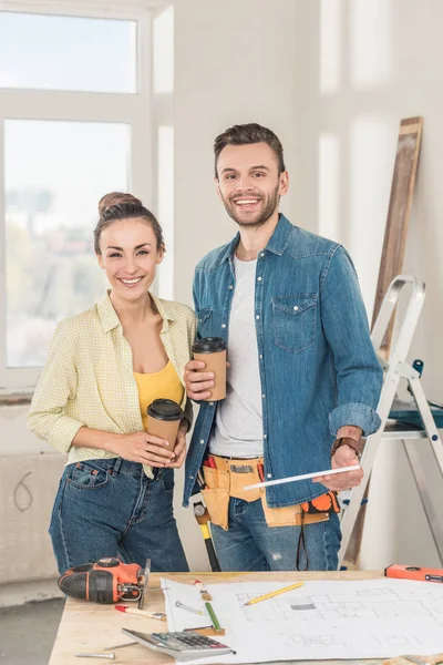 Glückliches junges Paar mit Coffee to go und digitalem Tablet im neuen Haus — Stockfoto