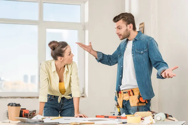 Émotionnel jeune homme gestuelle et querelle avec petite amie tout en discutant réparation de la maison — Photo de stock