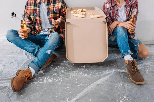 Schnappschuss von jungem Paar mit Bierflasche und Pizzaschachtel in neuer Wohnung — Stockfoto