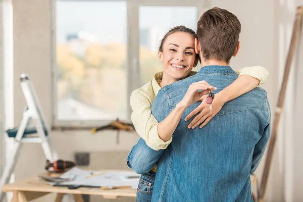 Feliz joven mujer abrazando novio y sosteniendo la llave de nuevo apartamento — Stock Photo
